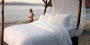 A bed with white linens beside a pool